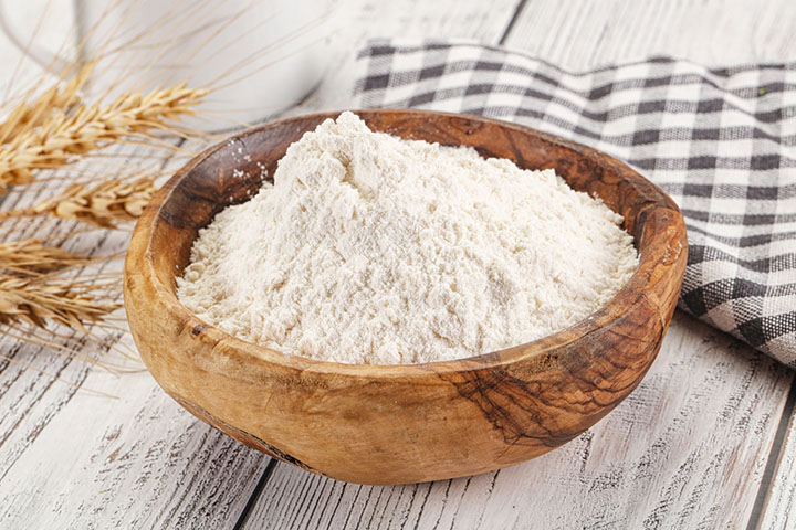 a wooden bowl filled with white flour on a table