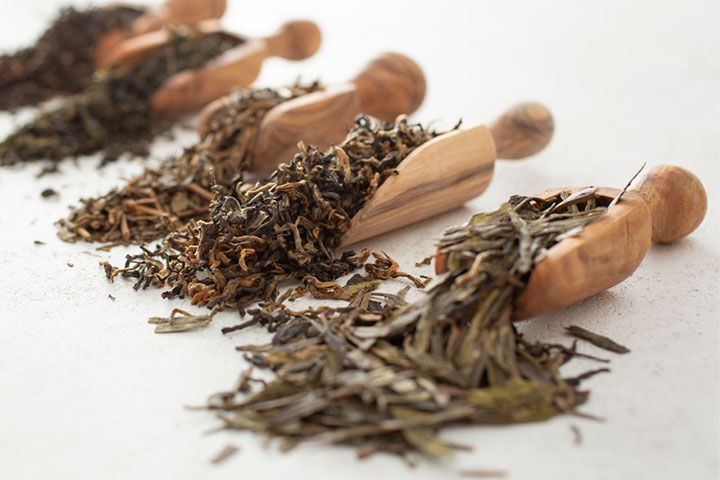 a row of wooden scoops overflowing with different types of dried tea leaves