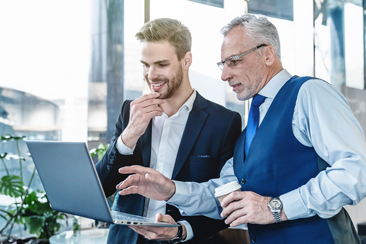 two men discussing while one is holding a laptop