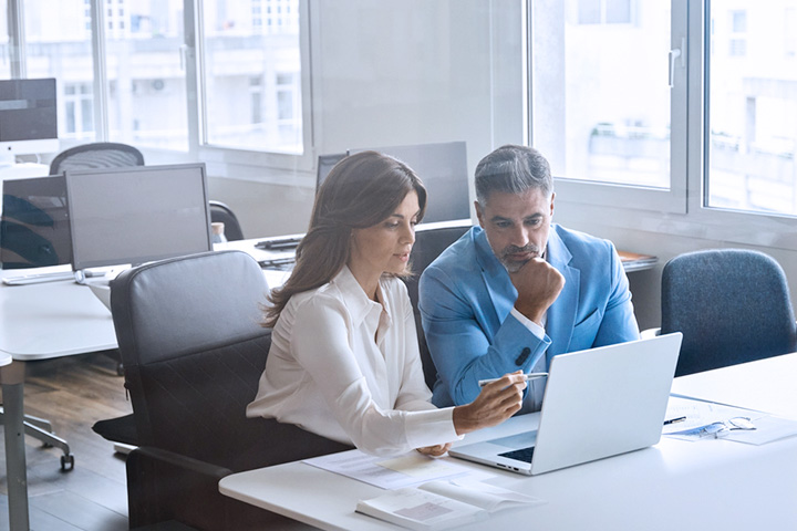 man and woman discussing in front of a laptop on an empty office space