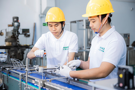 two workers installing parts on the filling machine assembly line