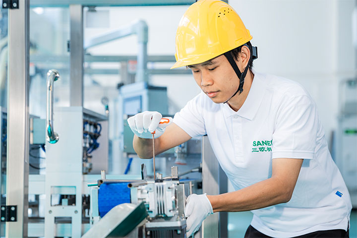 an assembly worker screwing a part of the coffee filling machine as part of the assembly process