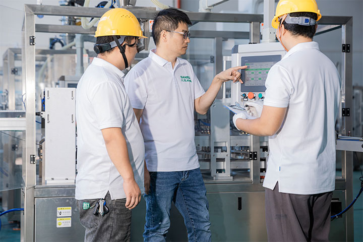 a Saneu technician showing two other employees the coffee machine interface