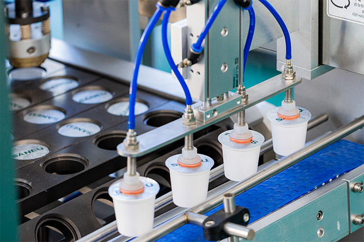 four filled coffee pods being moved from the production line into the inspection line