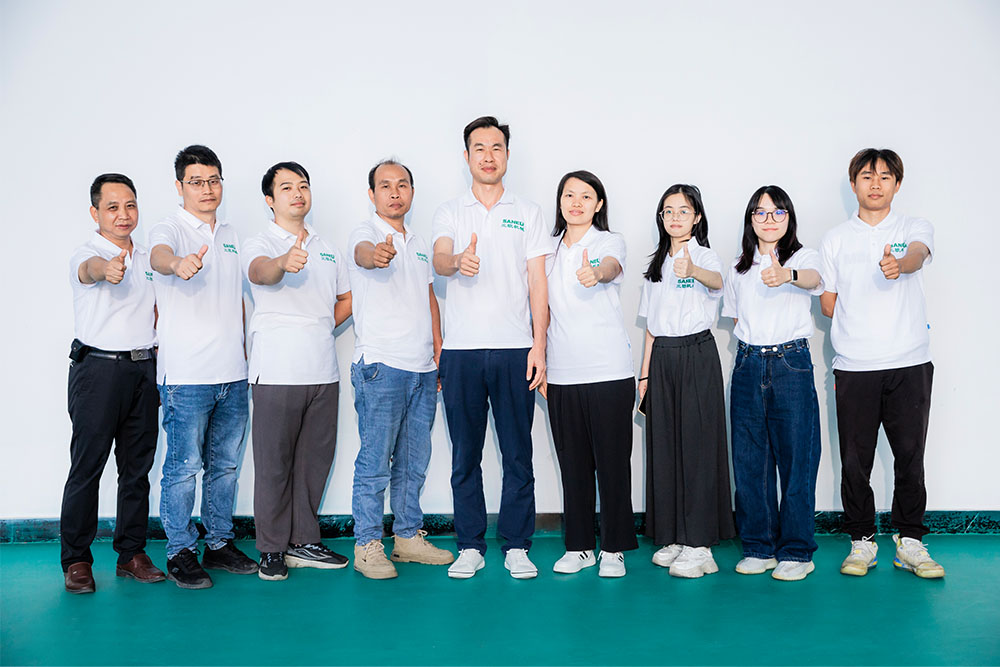 nine Saneu employees posing on a white background with their thumbs up