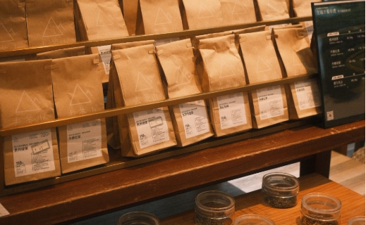several paper bags filled with coffee beans on a store's display stand