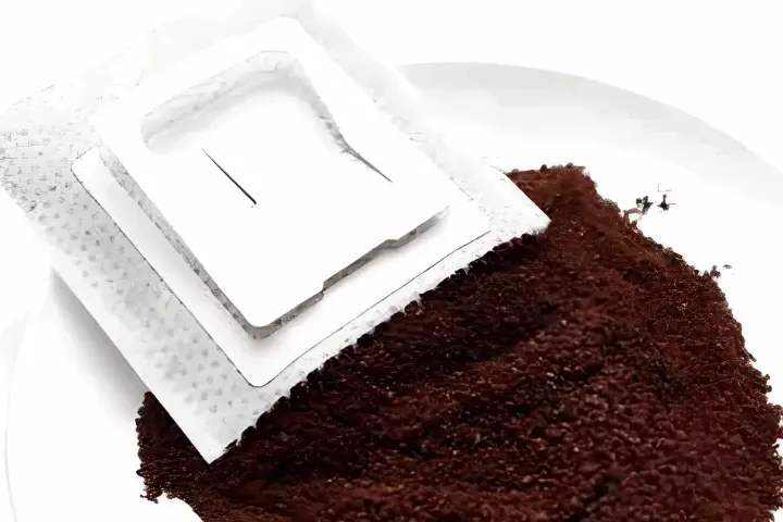single-serve drip coffee bag with ground coffee beans spilled